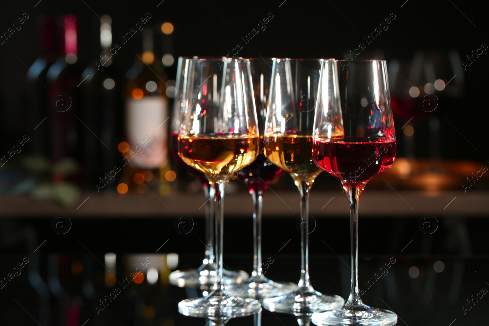 Photo of Glasses with different wines on bar counter against blurred background. Space for text