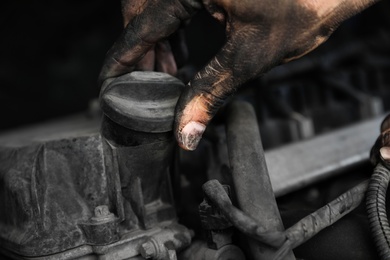 Photo of Dirty mechanic fixing car, closeup of hand