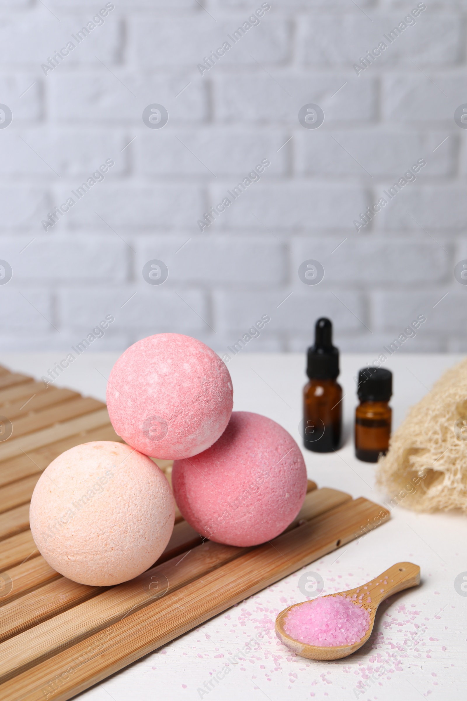 Photo of Beautiful aromatic bath bombs and sea salt on white table, space for text