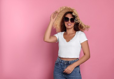 Photo of Happy beautiful woman with stylish straw hat and sunglasses on pink background, space for text