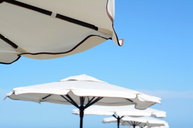 Photo of Beautiful white beach umbrellas against blue sky