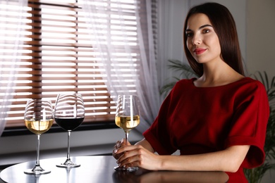 Photo of Beautiful young woman tasting luxury wine at table. Space for text