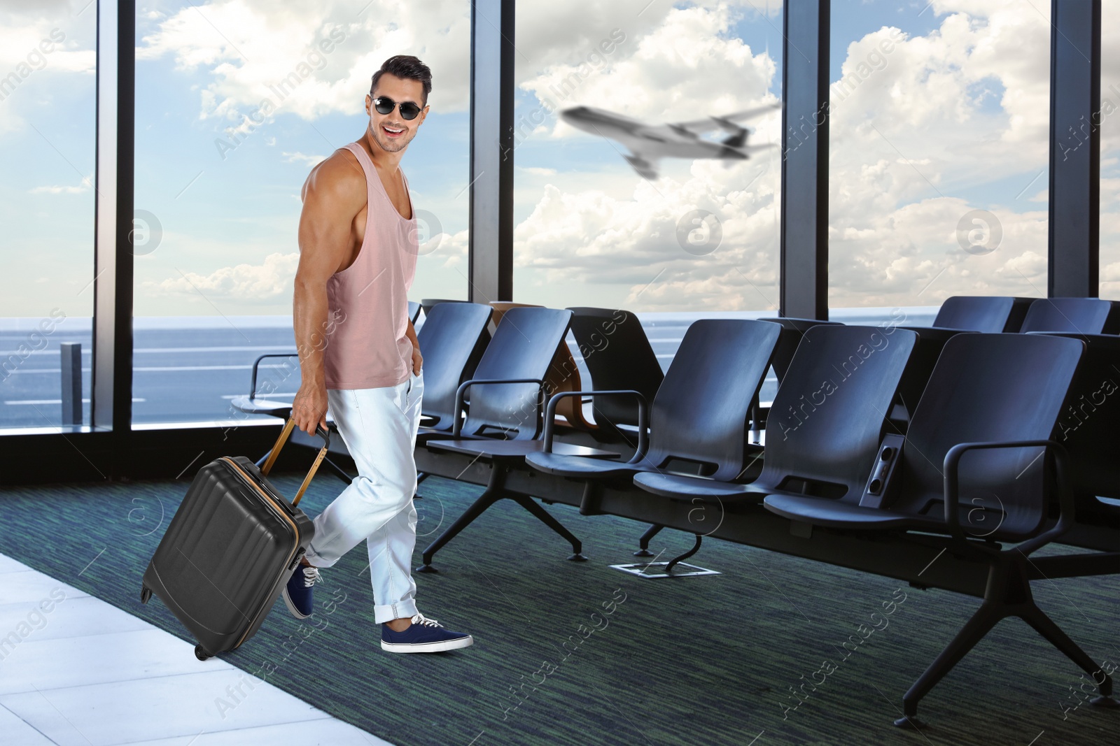 Image of Happy young man with suitcase in airport