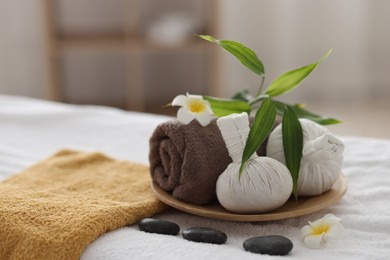 Spa stones, flowers and herbal bags on towel indoors, closeup