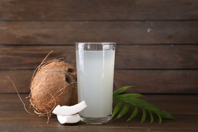 Photo of Glass of coconut water, leaf and nuts on wooden table