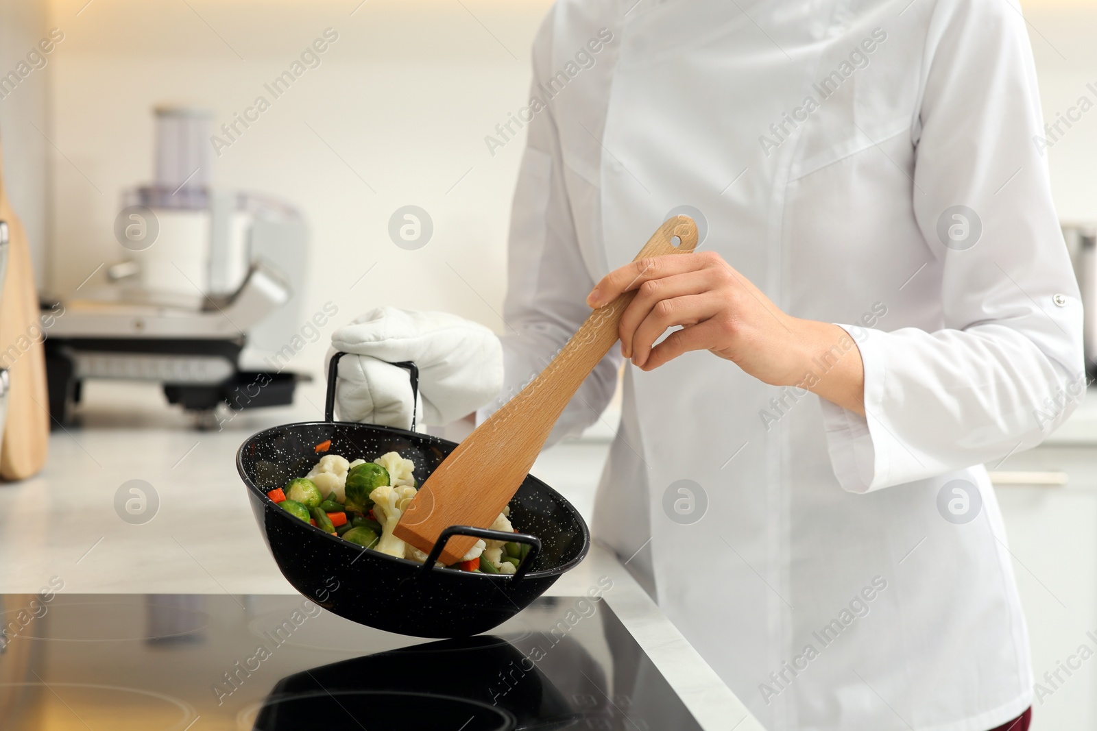 Photo of Professional chef stiring delicious dish in kitchen, closeup