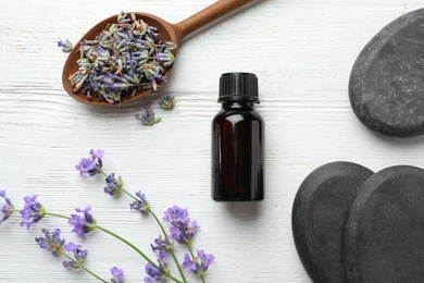 Flat lay composition with bottle of natural lavender essential oil on white wooden background