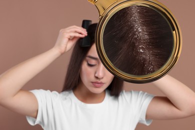 Image of Woman suffering from dandruff on pale brown background. View through magnifying glass on hair with flakes