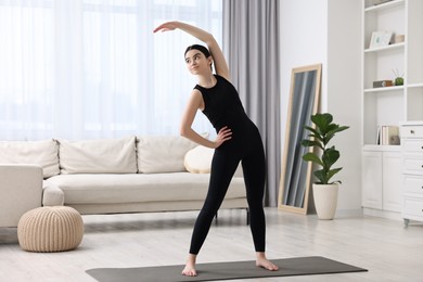 Photo of Girl stretching on yoga mat at home. Janu Sirsasana pose variation