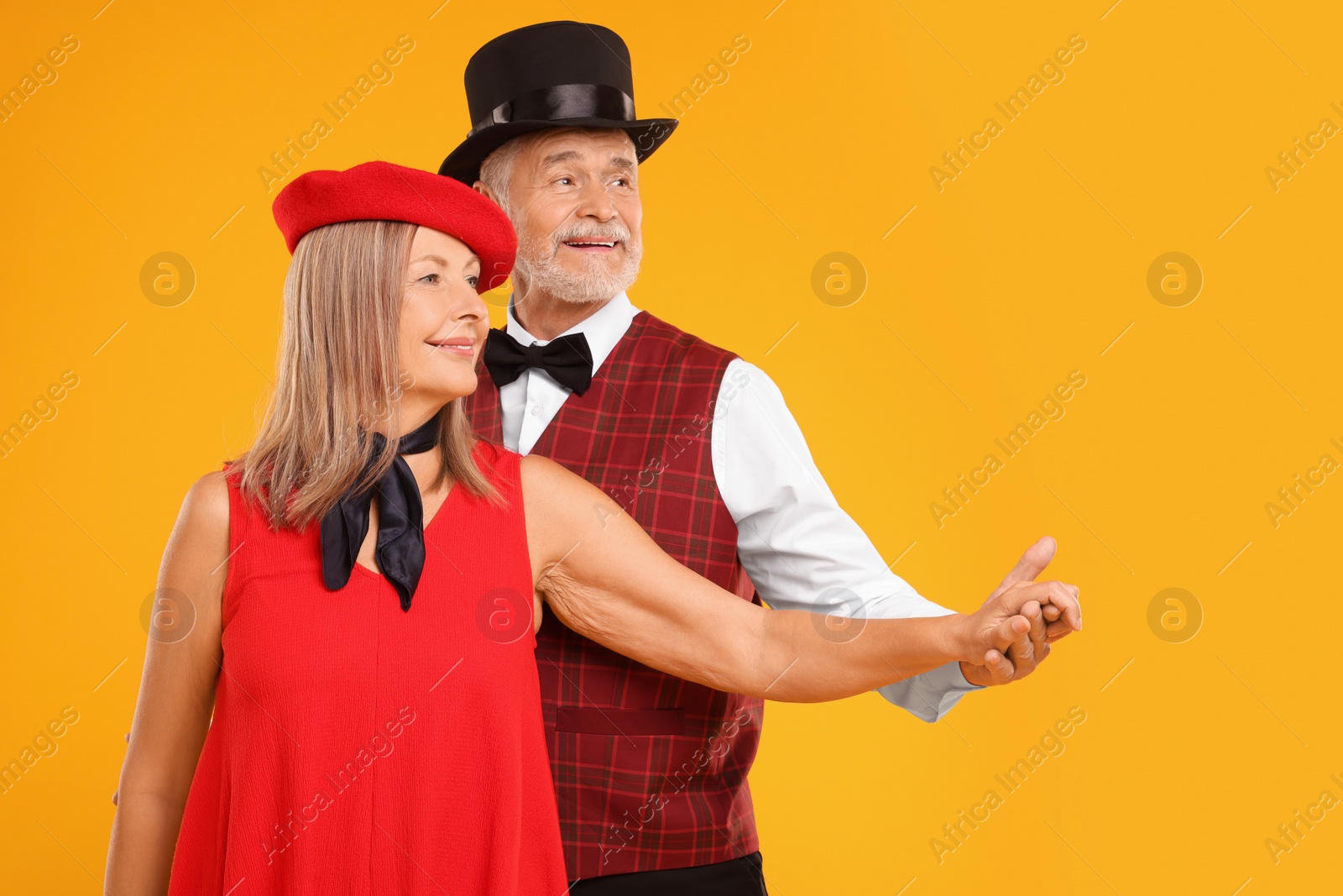 Photo of Senior couple dancing together on orange background