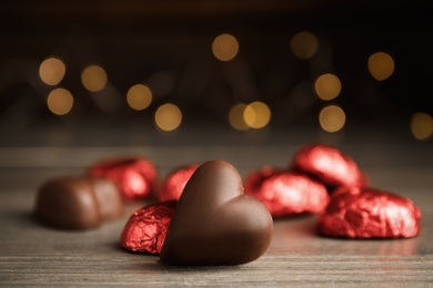 Photo of Tasty heart shaped chocolate candy on wooden table, closeup. Happy Valentine's day
