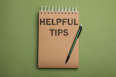 Image of Notebook with phrase Helpful Tips and pencil on green background, top view