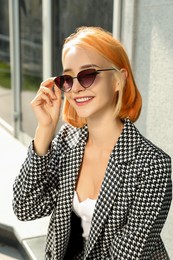Beautiful young woman with bright dyed hair in sunglasses outdoors