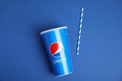 Photo of MYKOLAIV, UKRAINE - JUNE 9, 2021: Paper Pepsi cup and straw on blue background, flat lay
