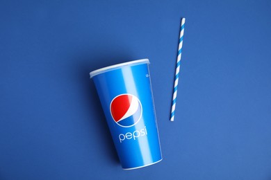 MYKOLAIV, UKRAINE - JUNE 9, 2021: Paper Pepsi cup and straw on blue background, flat lay