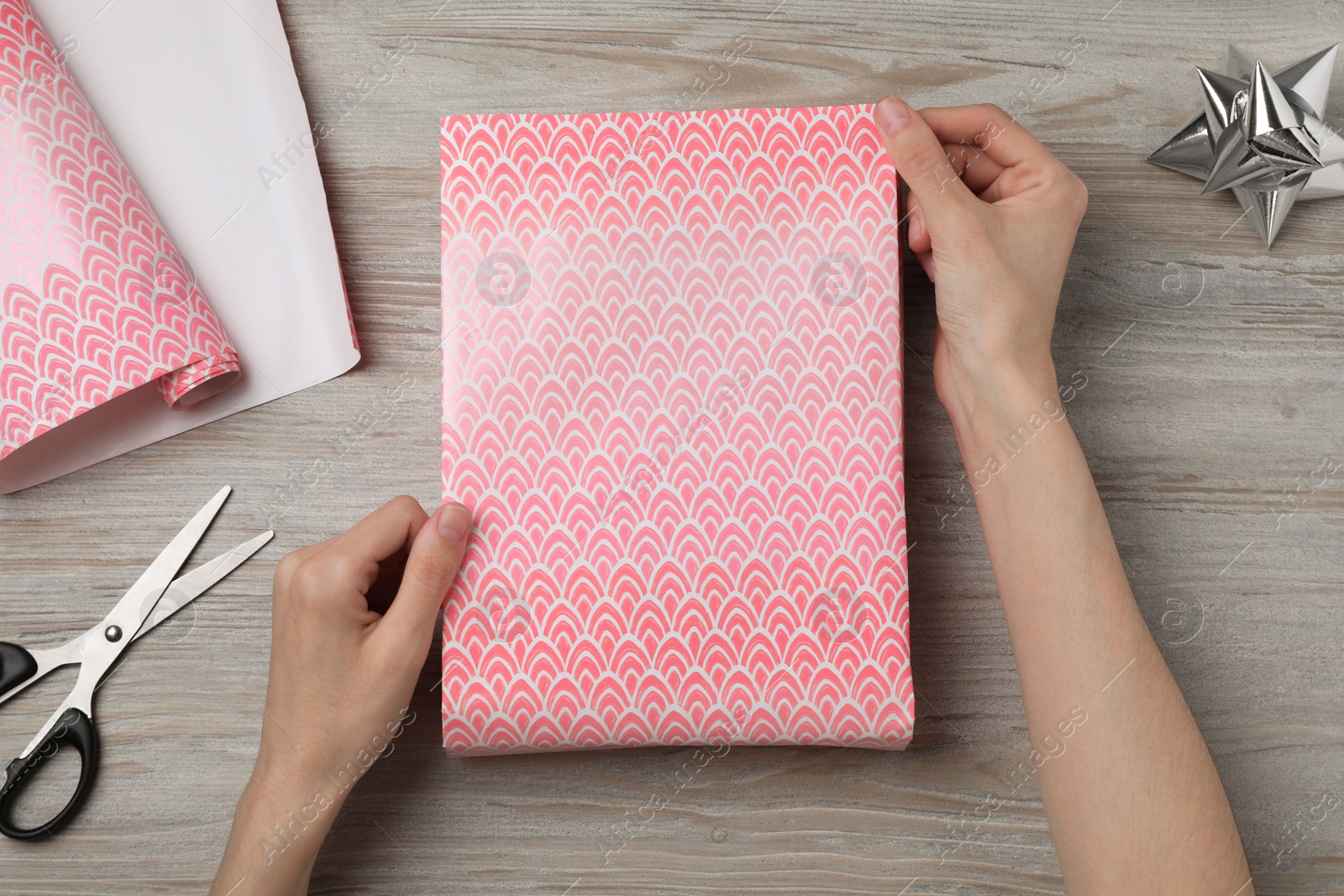 Photo of Woman wrapping gift with beautiful paper at wooden table, top view