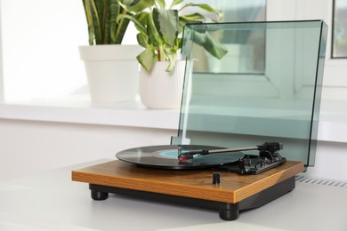 Photo of Stylish turntable with vinyl disc on white table at home, space for text