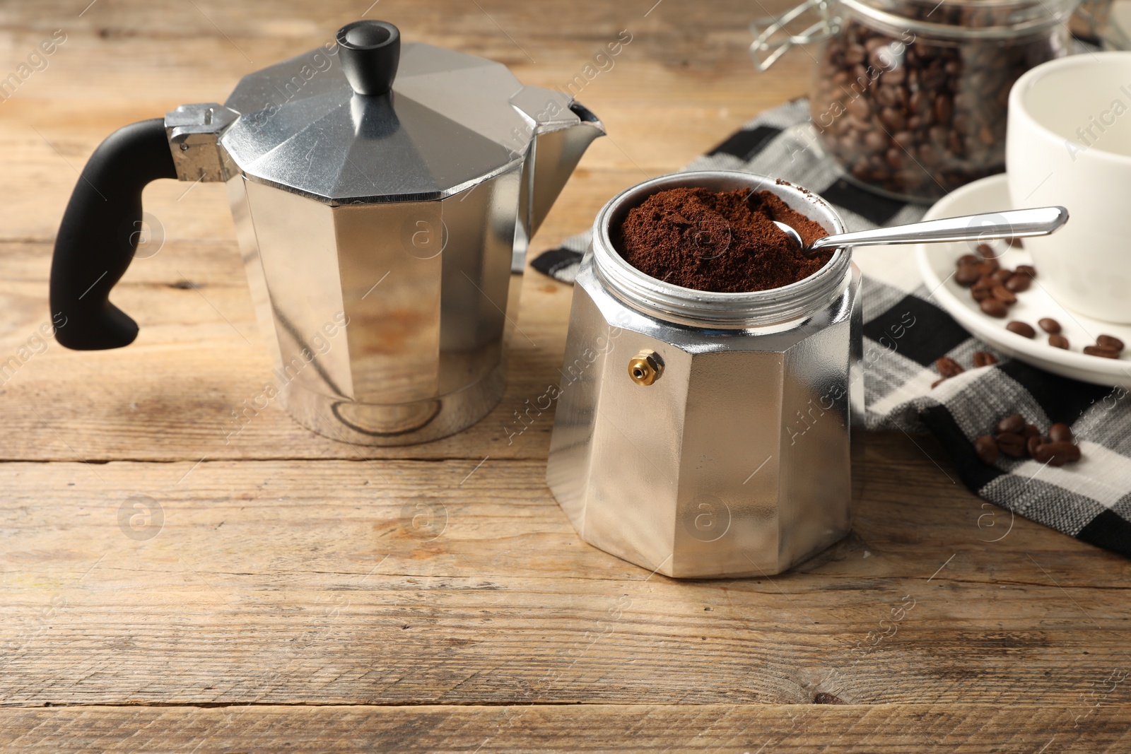 Photo of Moka pot with ground coffee on wooden table