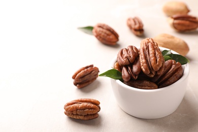 Photo of Ripe pecan nuts in dish served on light table. Space for text
