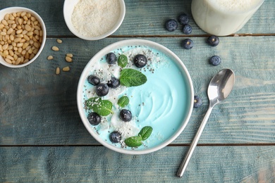 Flat lay composition with bowl of spirulina smoothie on wooden table