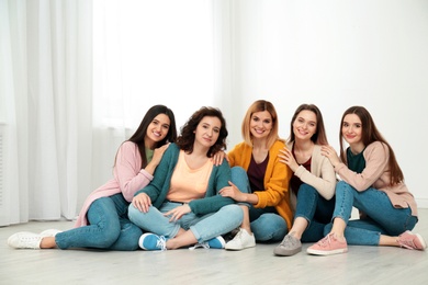 Photo of Portrait of happy ladies sitting on floor indoors. Women power concept