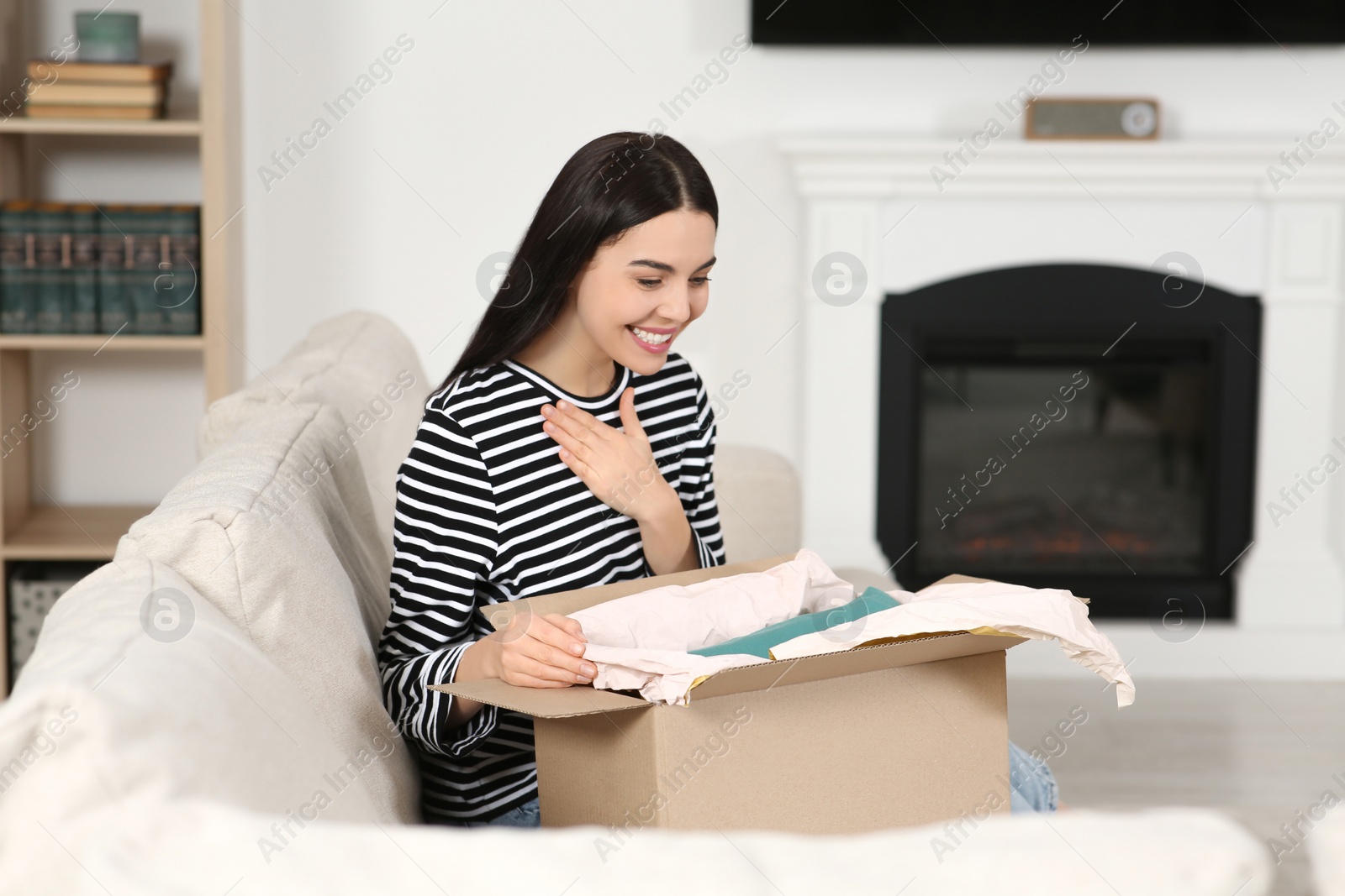 Photo of Happy young woman with parcel at home. Internet shopping