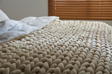 Soft chunky knit blanket on bed indoors