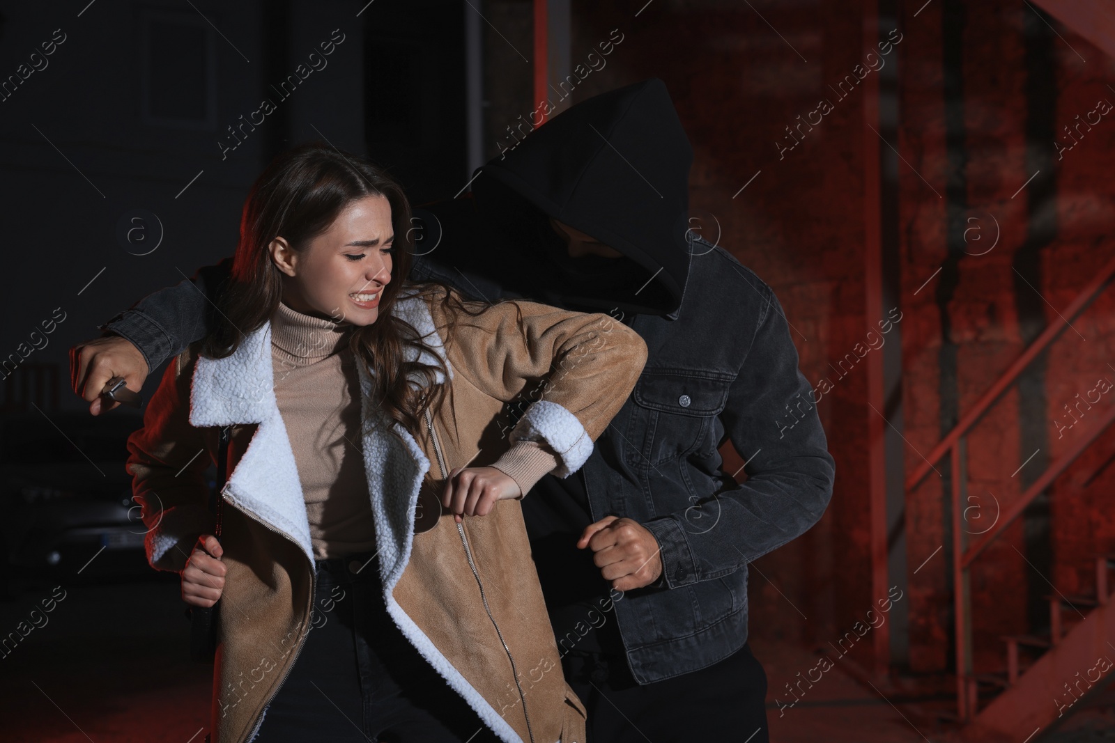 Photo of Woman defending herself from attacker with knife outdoors at night