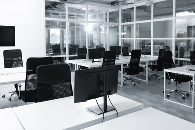 Photo of Stylish interior of open plan office. Workspace with computers, tables and chairs