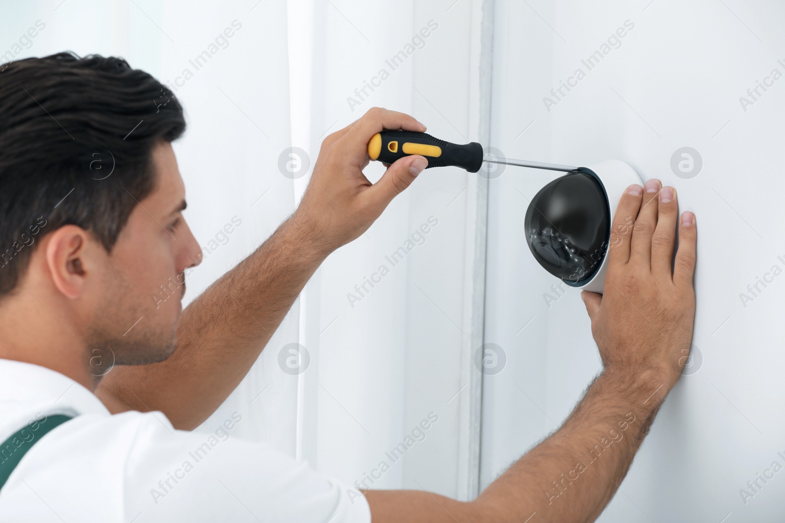 Photo of Technician installing CCTV camera on wall indoors