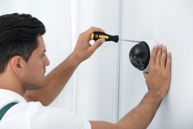 Technician installing CCTV camera on wall indoors