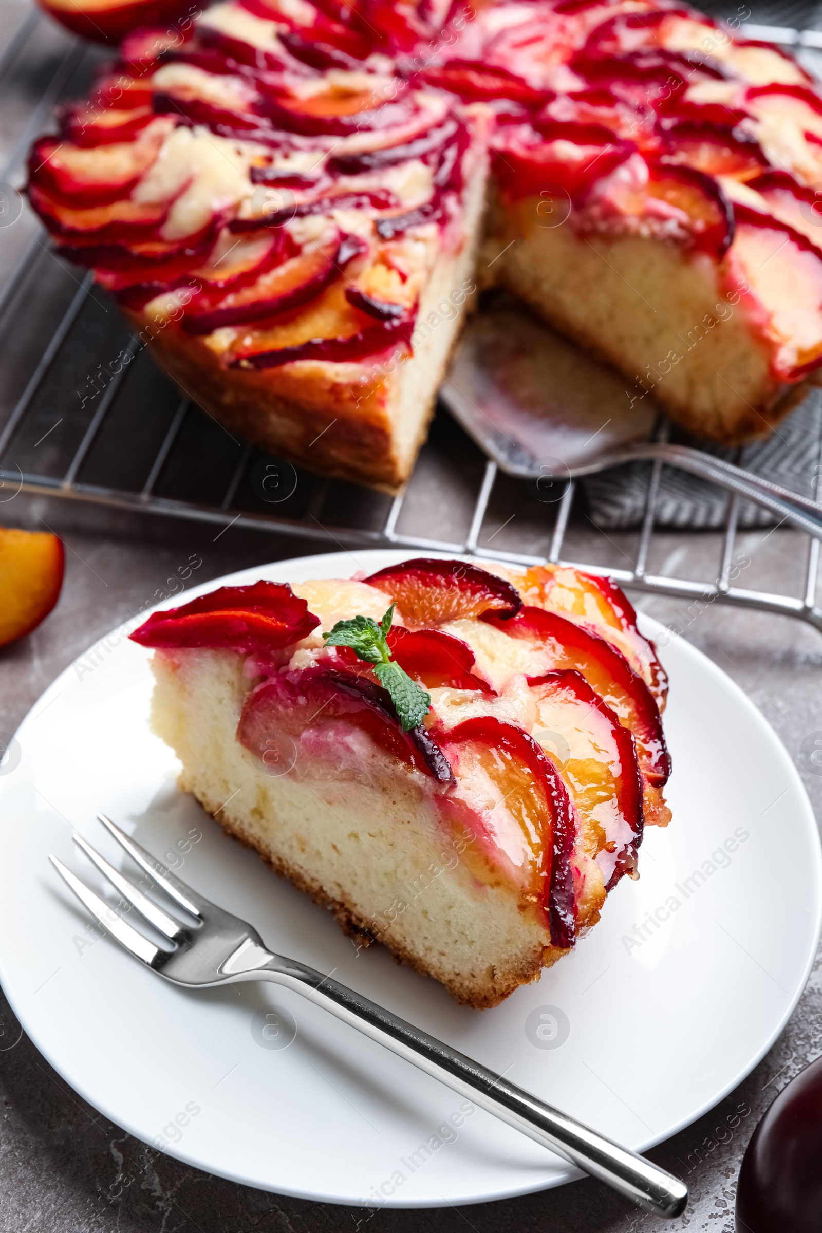 Photo of Slice of delicious cake with plums on table, closeup