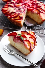 Slice of delicious cake with plums on table, closeup