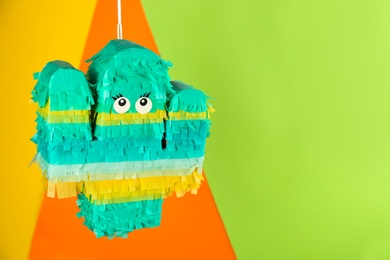 Cactus shaped pinata hanging on color background. Space for text