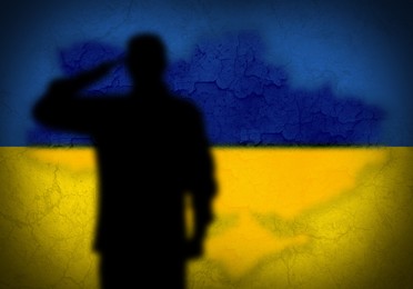 Image of Silhouette of soldier with Ukrainian flag colors on background, space for text. Military service during war