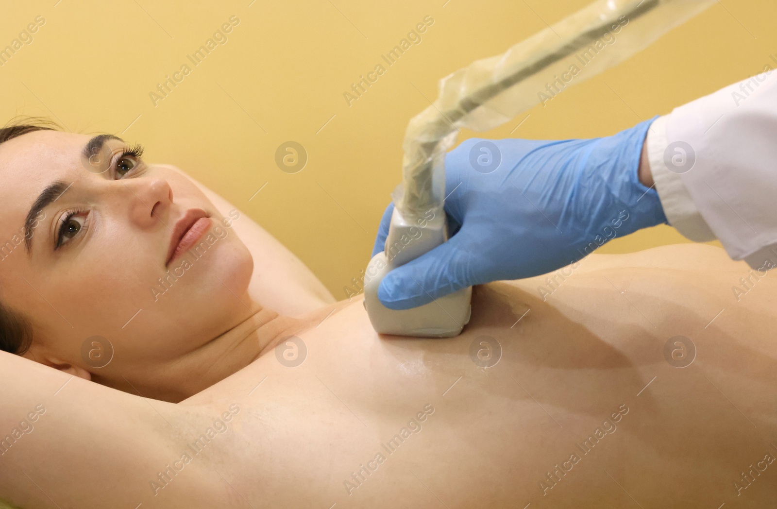 Photo of Mammologist conducting ultrasound examination of woman's breast in clinic, closeup