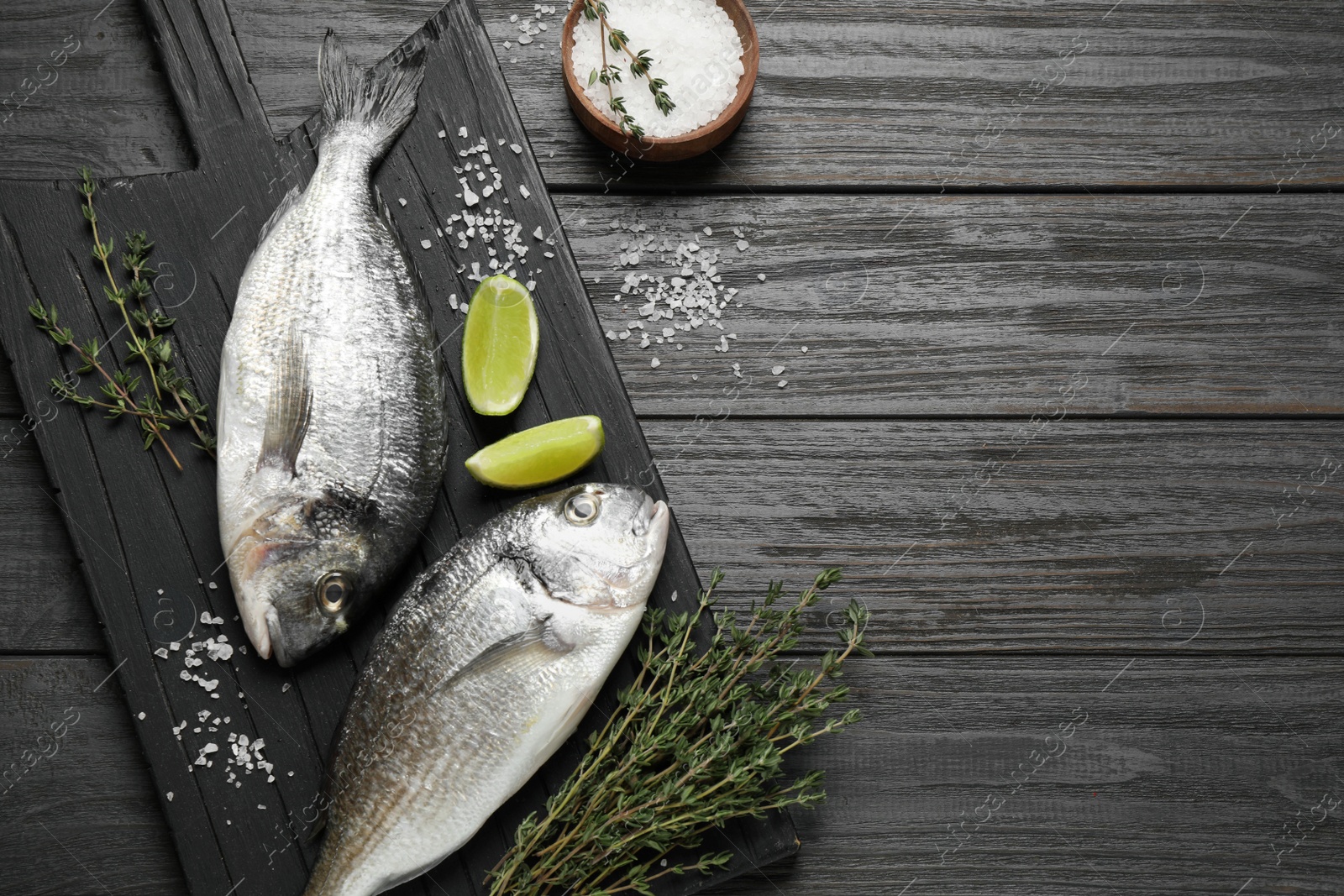 Photo of Raw dorada fish on black wooden table, flat lay. Space for text