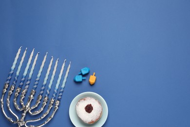 Flat lay composition with Hanukkah menorah on blue background. Space for text