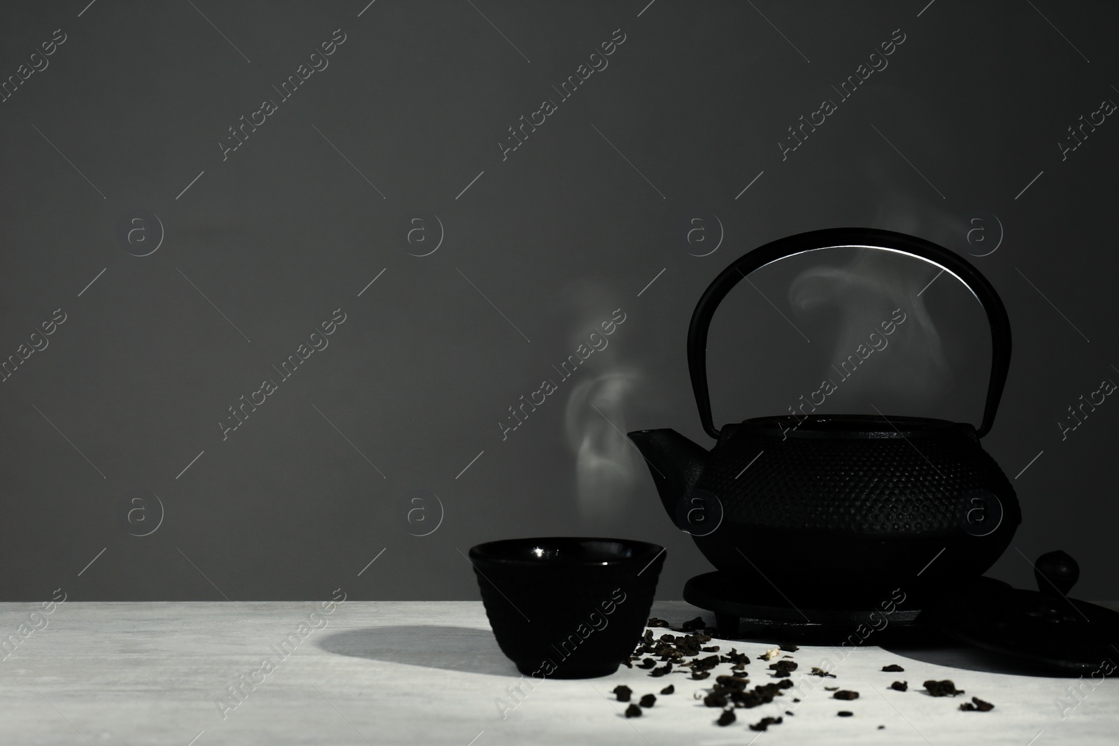 Photo of Oriental teapot and cup on table against grey background, space for text