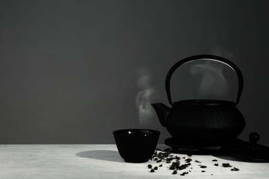 Oriental teapot and cup on table against grey background, space for text