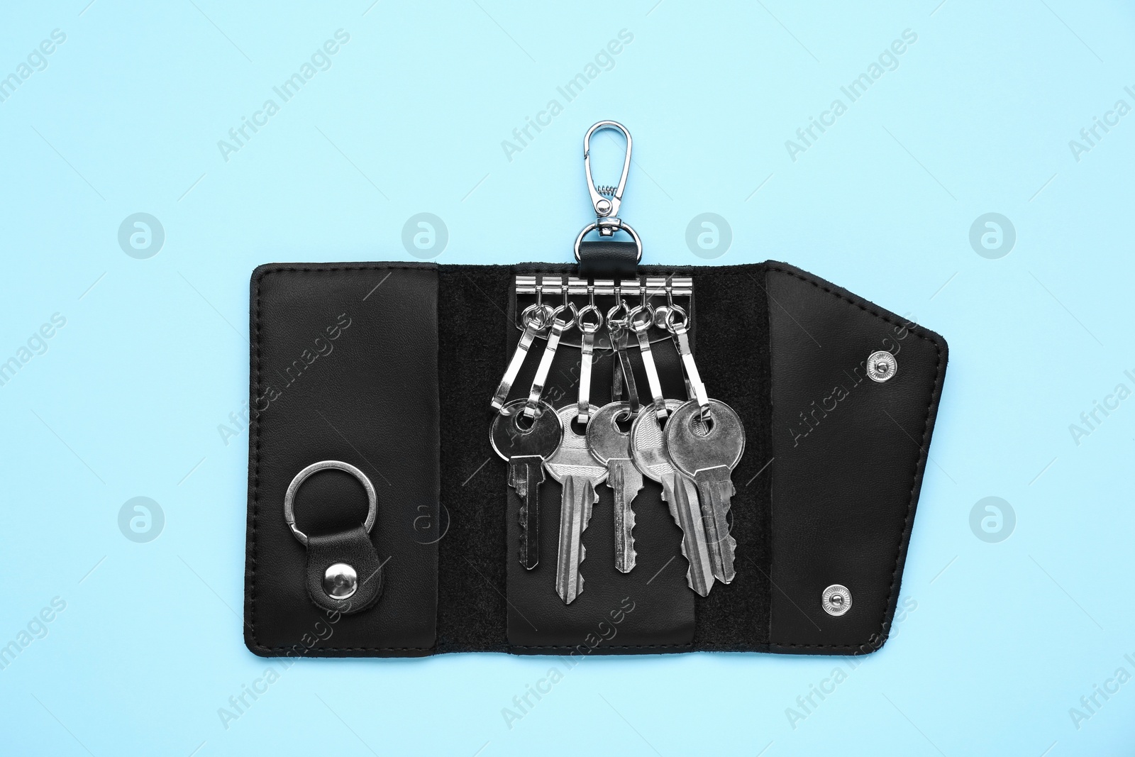 Photo of Leather holder with keys on light blue background, top view