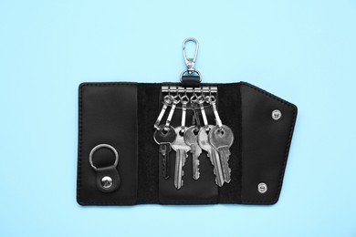 Leather holder with keys on light blue background, top view