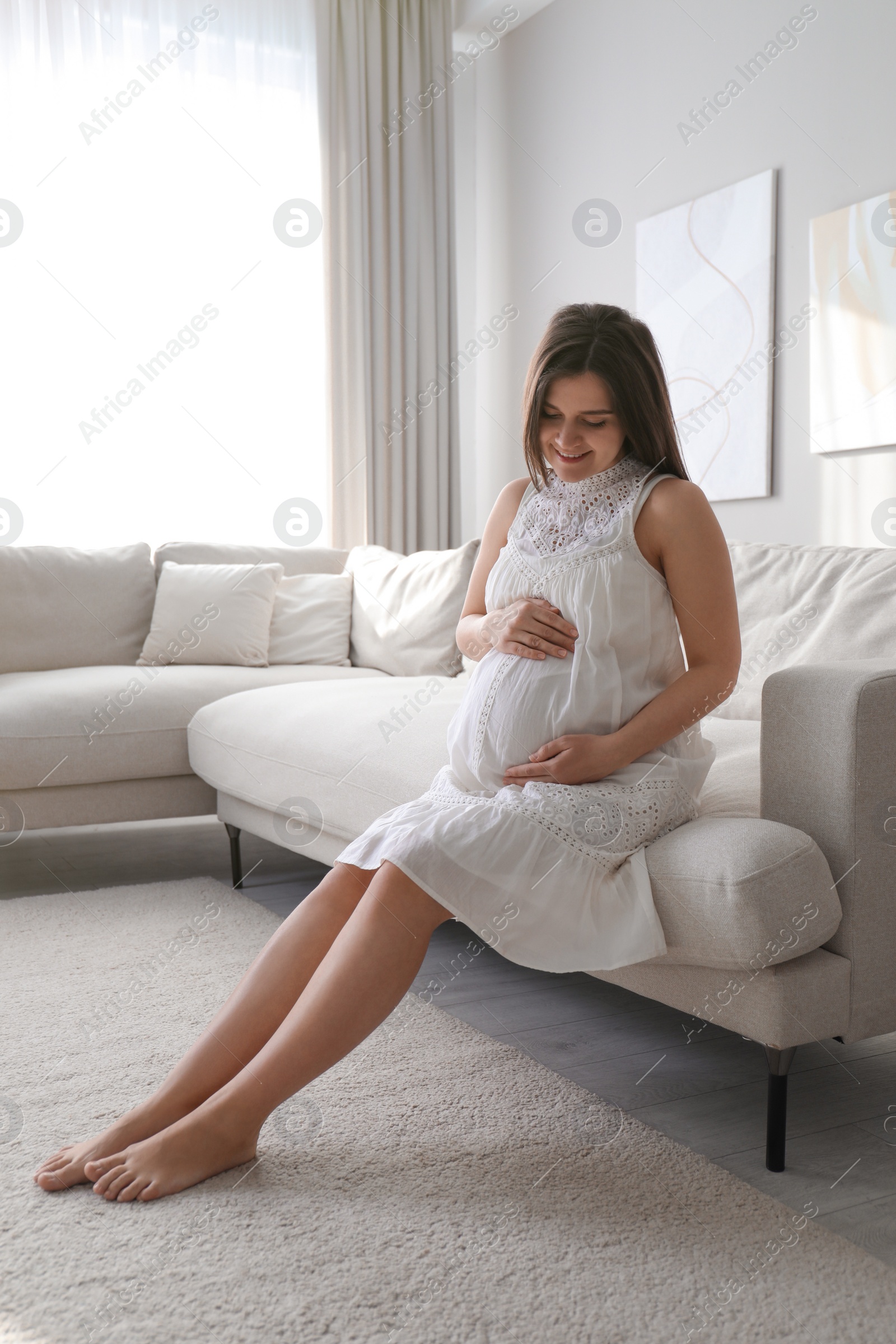 Photo of Pregnant young woman touching belly at home