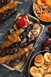 Photo of Delicious sweet churchkhelas and ingredients on textured table, flat lay