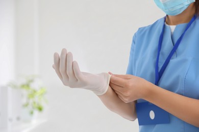 Photo of Doctor putting on medical gloves against blurred background, closeup