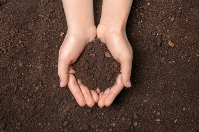 Photo of Woman holding pile of soil above ground, top view