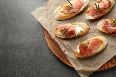 Board with tasty bruschettas on grey table, top view. Space for text