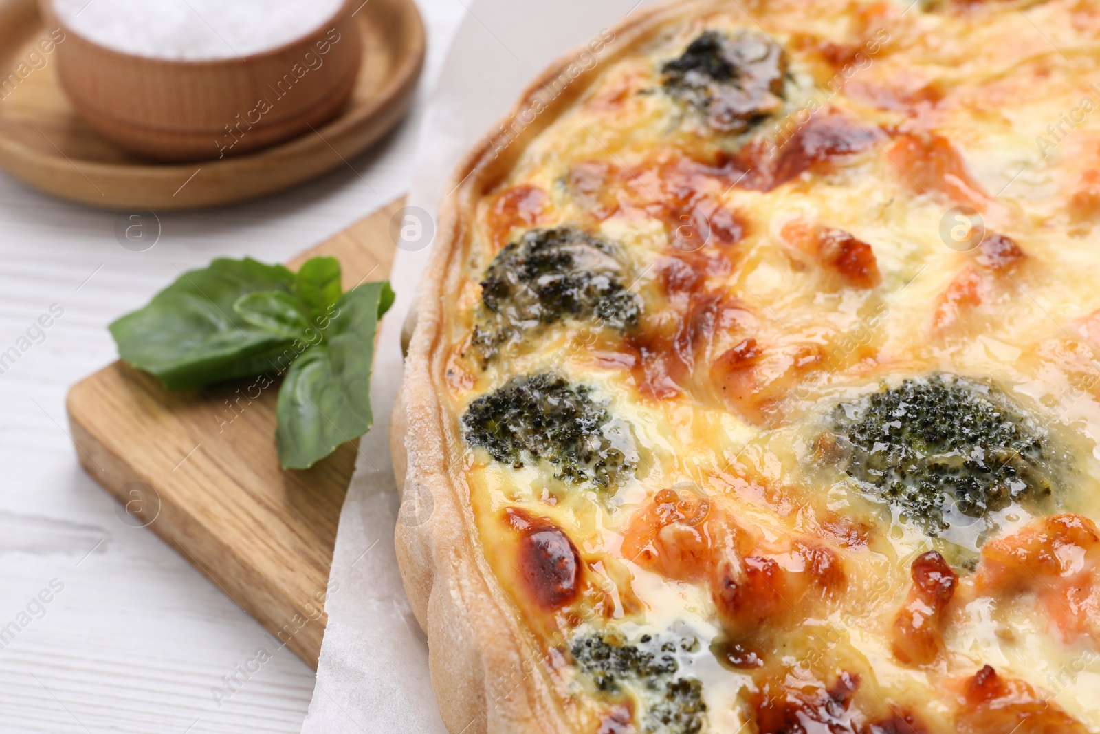Photo of Delicious homemade quiche with salmon and broccoli on white table, closeup