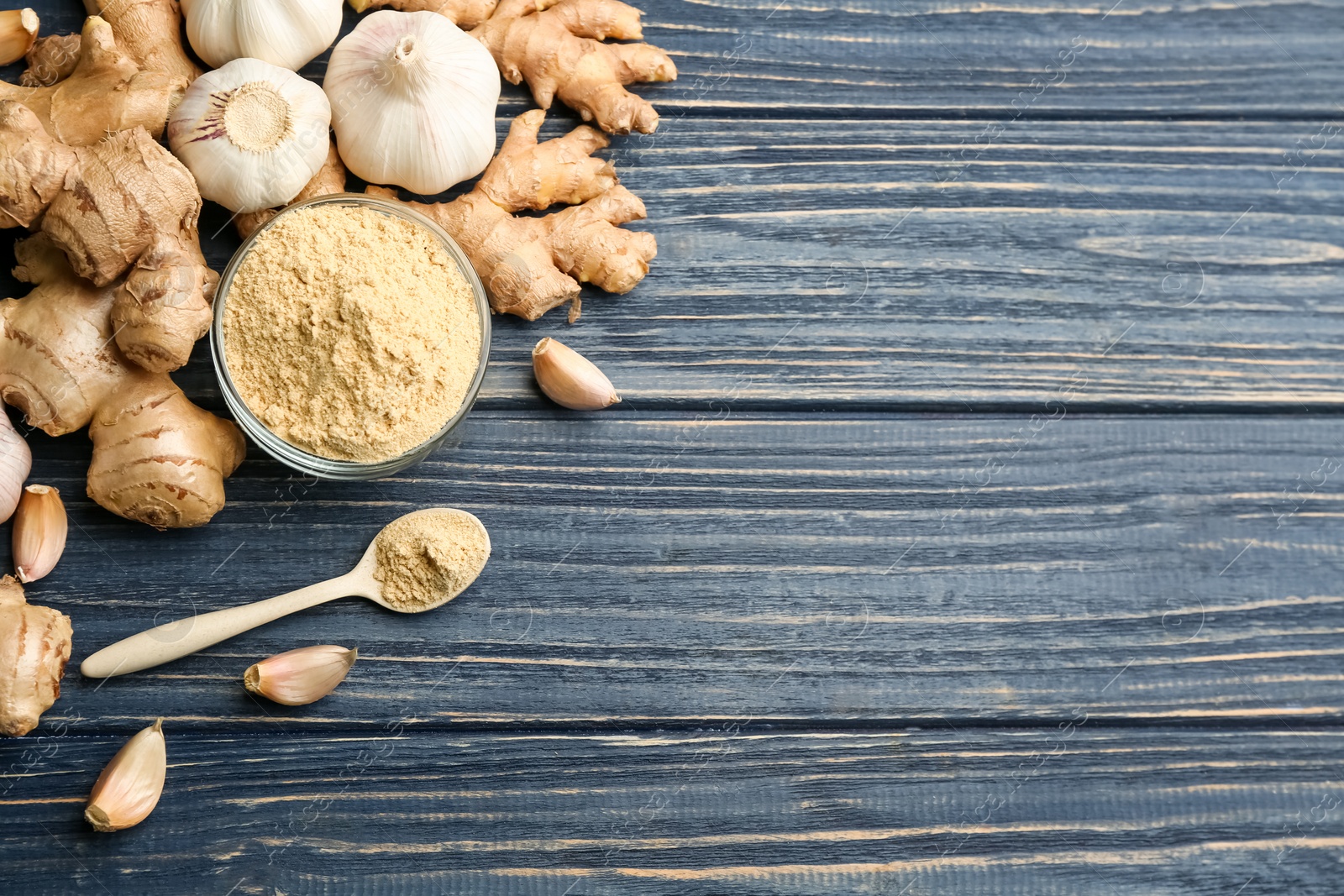 Photo of Fresh garlic, ginger roots and powder on blue wooden table, flat lay with space for text. Natural cold remedies