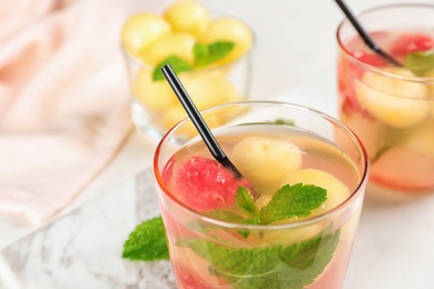 Photo of Glass with tasty watermelon and melon ball drink on table, closeup